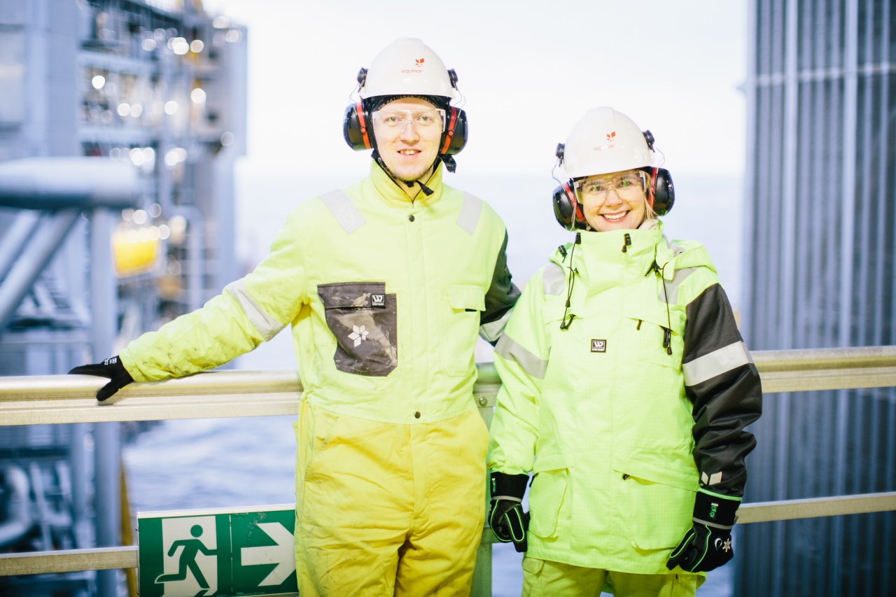 Photo of two people in protective gear standing at a railing and smiling