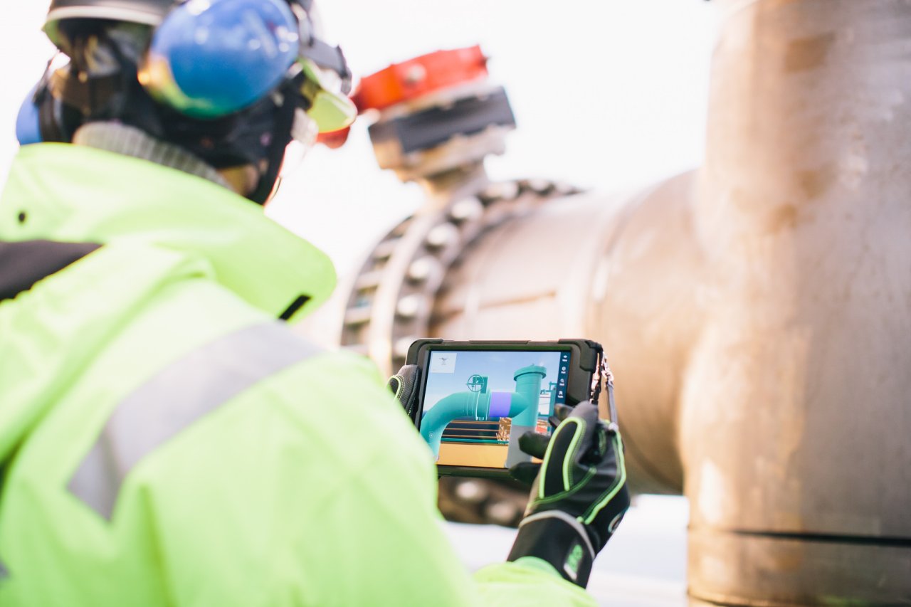 Photo of a person in protective gear using a tablet with a model of a valve on it
