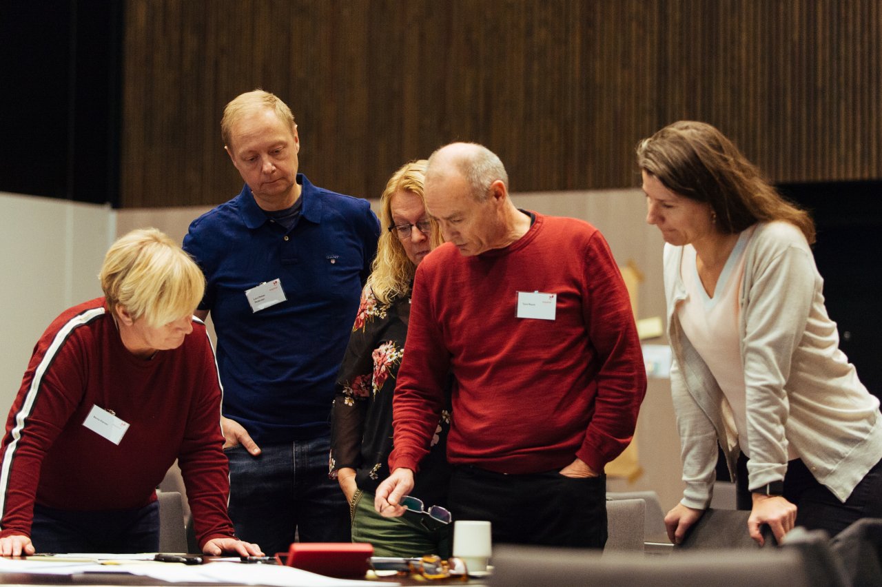 Photo of a group of people having a discussion during a workshop while standing over a table