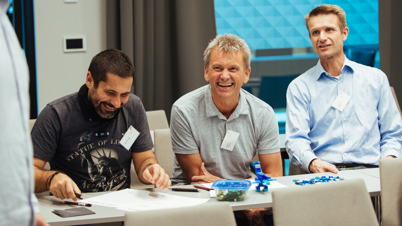 Photo of three smiling people working together during a conference