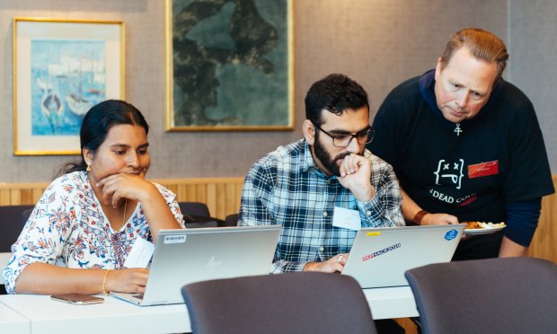 A woman and two men working on their laptops during Equinor Developer Conference