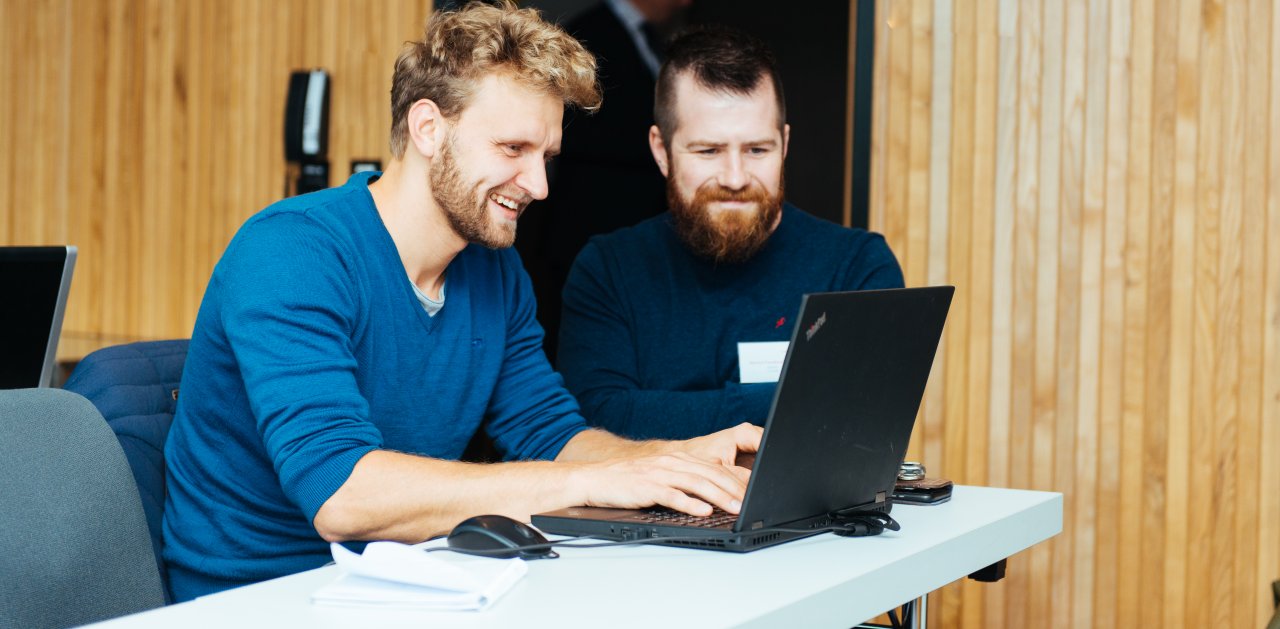 Two men looking at the same computer during Equinor Developer Conference