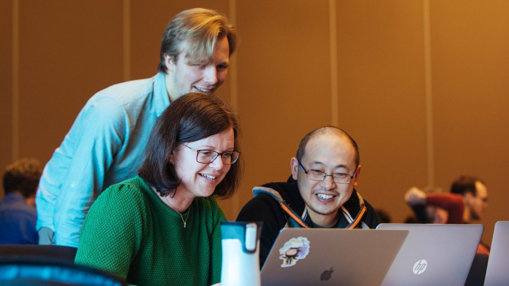 A team of three Equinor software developers working together in a workshop
