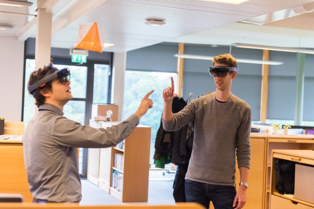 Photo of two colleagues wearing Microsoft Hololens glasses and staring into thin air while making hand gestures