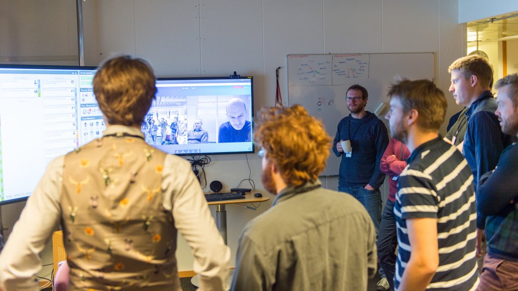 A group of people gathered in front of a display during a video conference