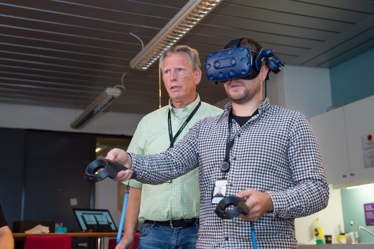 Two people in an office landscape one of which is wearing a VR landscape 