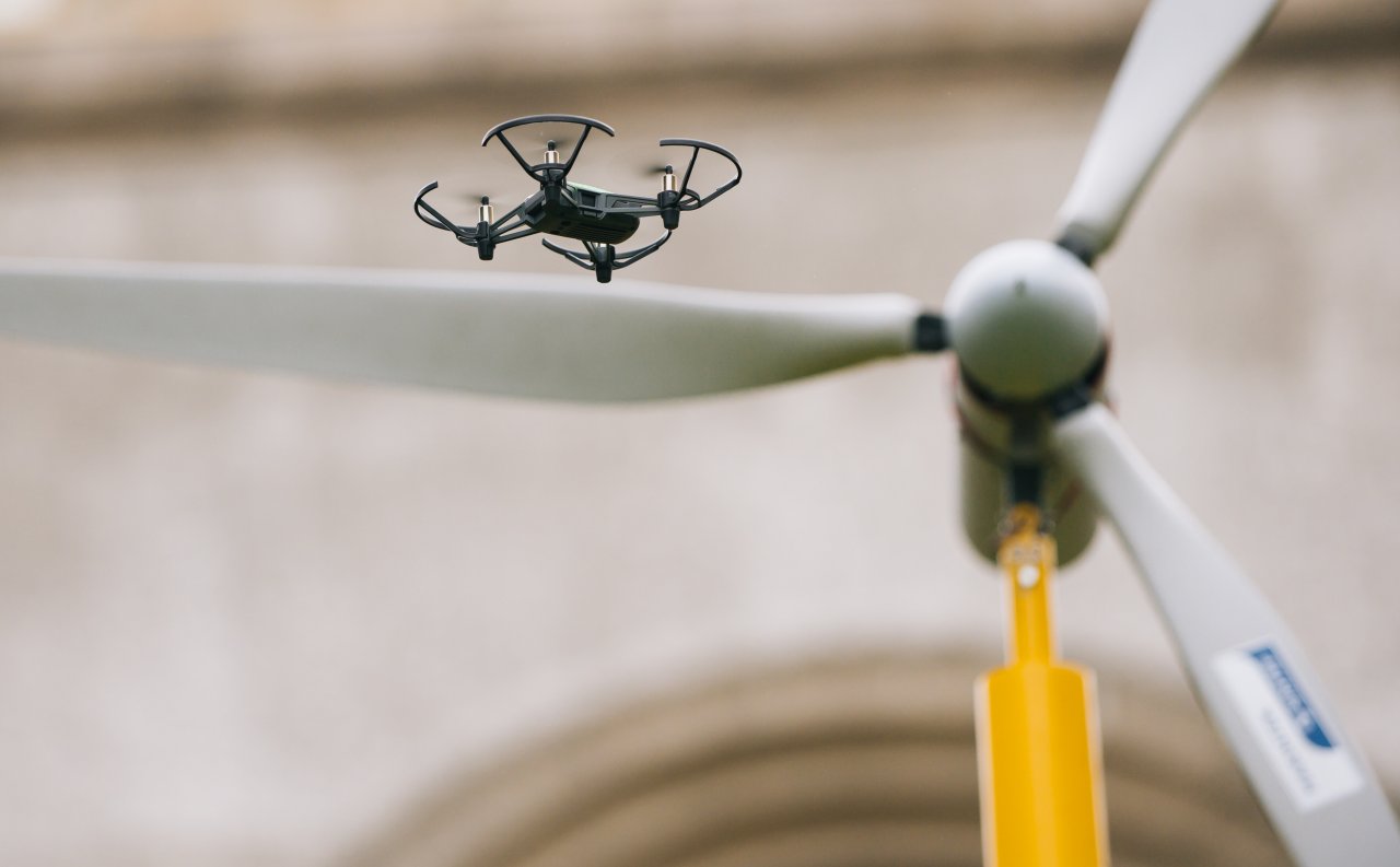A small drone flying near a wind turbine model during Techathon2019, a hackathon hosted by Equinor